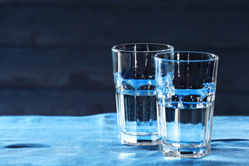 Two glasses of water on table on wooden background