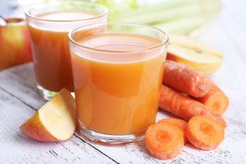 Glasses of juice with apple and carrot on wooden table close up