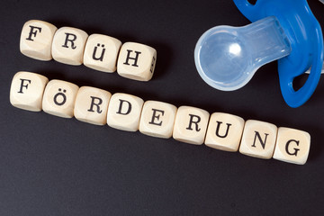 Nuckel und Kreidetafel mit den Worten Früh Förderung