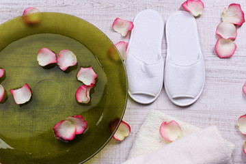 Spa bowl with water, rose petals, towel and slippers