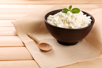 Cottage cheese in bowl with spoon on napkin on wooden