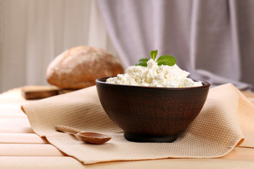 Cottage cheese in bowl with bread on table on fabric background