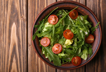 Salad with arugula and cherry tomatoes on wooden table