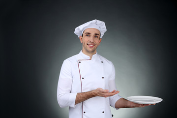 Chef with plate in hand on dark background