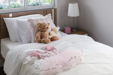 girl's bedroom with doll and dress on wooden bed