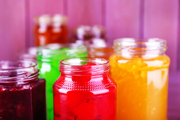 Fototapeta na wymiar Homemade jars of fruits jam on color wooden background