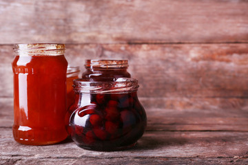 Homemade jars of fruits jam on rustic wooden background