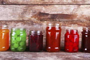 Homemade jars of fruits jam on rustic wooden background