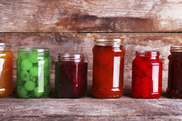 Homemade jars of fruits jam on rustic wooden background