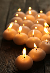 Fototapeta na wymiar Burning candles on wooden table close-up