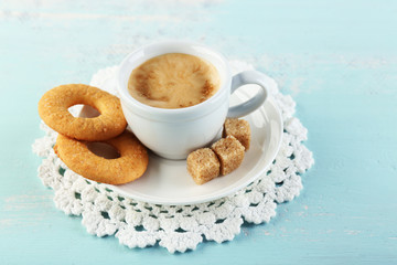 Cup of coffee and tasty cookie on color wooden background