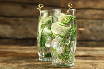 Glasses with fresh organic cucumber water on wooden table