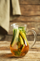 Glass ewer with fresh organic cucumber water on wooden table