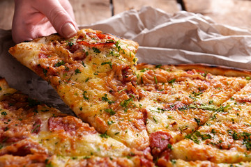 Female hand holding slice of pizza close up
