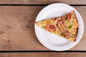 Tasty slice of pizza on plate on wooden table
