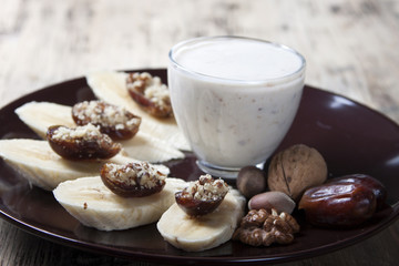 Bananas with dates , nuts and a cup of yogurt.