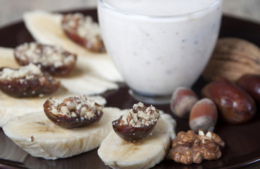 Bananas with dates , nuts and a cup of yogurt.