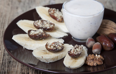 Bananas with dates , nuts and a cup of yogurt.