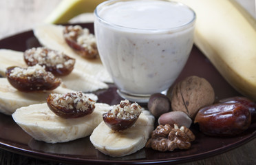 Bananas with dates , nuts and a cup of yogurt.