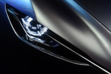 Predatory car headlight and hood of powerful sports grey car