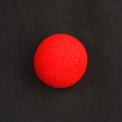 Red clown nose on black background