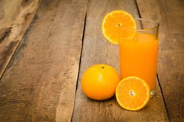 Orange juice in glass , fresh fruits on wooden background