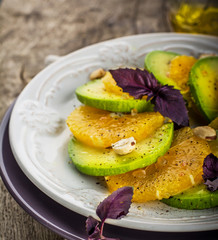 Appetizer of avocado, orange with purple basil and hazelnuts