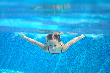 Child swims in pool underwater, girl swimming
