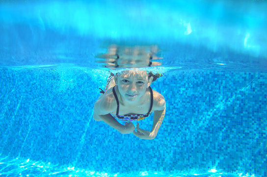 Child swims in pool underwater, girl swimming
