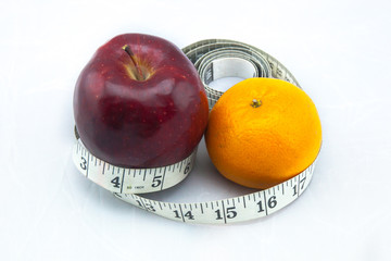 Red Apple and Orange with Measure Tape on White Background