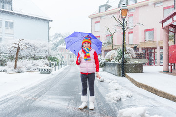 Outdoor portrait of a pretty little girl under the snowfall