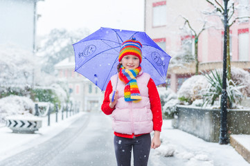 Outdoor portrait of a pretty little girl under the snowfall