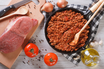 Bolognese sauce in a pan and ingredients horizontal top view