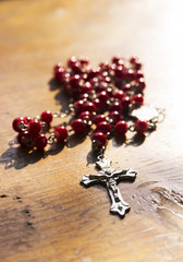 Rosary with red beads on wooden table