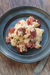 Risotto with sausage, cured ham and rosemary on a tin plate.