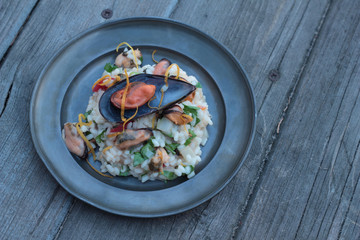 Risotto with seafood, chili and parsley on a tin plate.