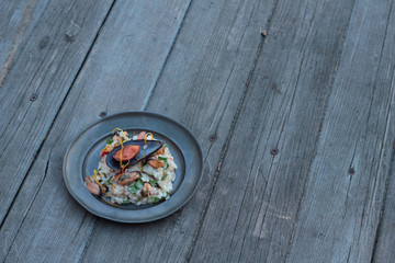 Risotto with seafood, chili and parsley on a tin plate.