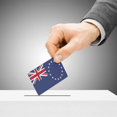 Voting concept - Male inserting flag into ballot box - Cook Isla
