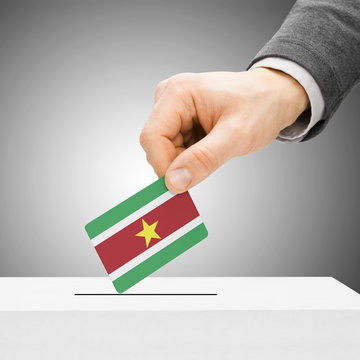 Voting concept - Male inserting flag into ballot box - Suriname