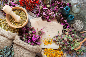 Healing herbs in hessian bags, wooden mortar, bottles with tinct - obrazy, fototapety, plakaty