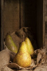 Pears in rustic kitchen setting with wooden box and hessian sack
