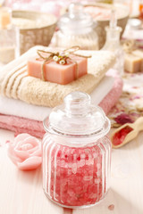 Fototapeta na wymiar Glass jar of pink sea salt on white wooden table