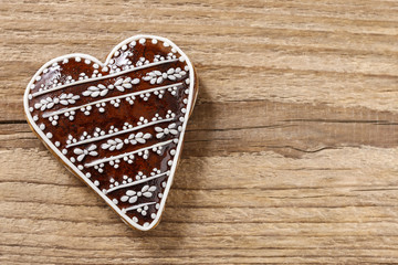 Gingerbread cookie in heart shape on a wooden background
