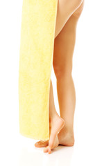 Female legs covered with a yellow towel