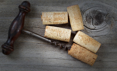 Antique corkscrew with used corks on aged wood