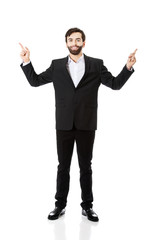 Happy businessman points his finger up.