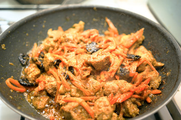 Restaurant cooking meat with carrot in frying pan