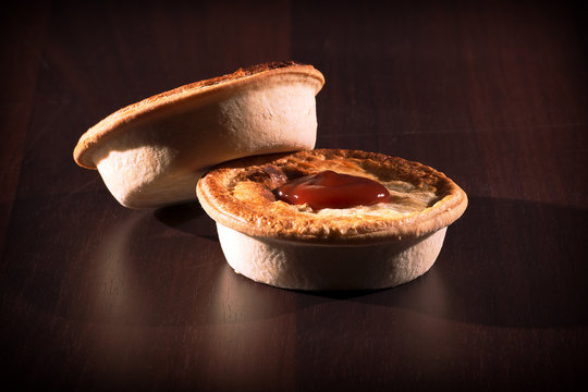 Freshly baked meat pies with sauce and high contrast lighting.