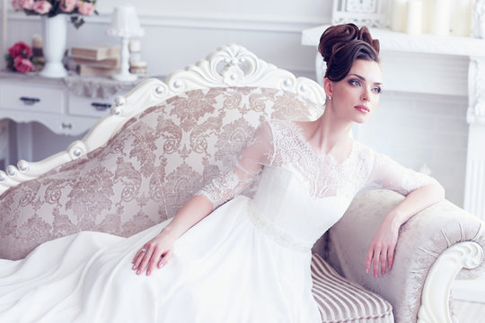 Young gorgeous bride is sitting in antique couch