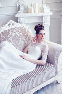 Young gorgeous bride is sitting in antique couch